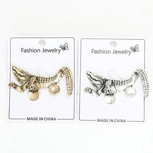 Detailed macro view of gold and silver crocodile brooches with rhinestone accents