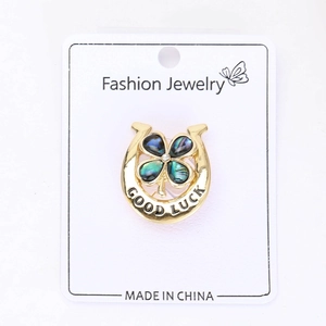 Détail d'une broche fer à cheval avec trèfle bleu et inscription Good Luck