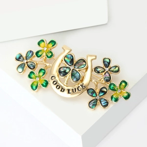 Golden horseshoe four-leaf clover brooch with iridescent shell inlays on white stand