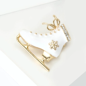 Detailed macro view of enamel ice skate brooch with gold snowflake and inset crystals