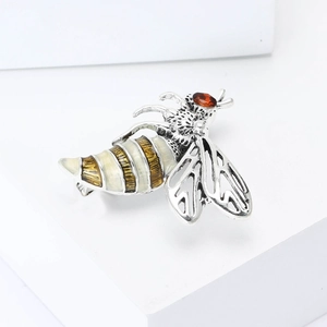 Detailed macro view of bee brooch showing hollow wings and faceted red gemstone eyes