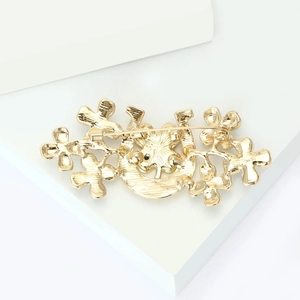 Detailed back view of a golden four-leaf clover brooch showing the secure safety pin clasp