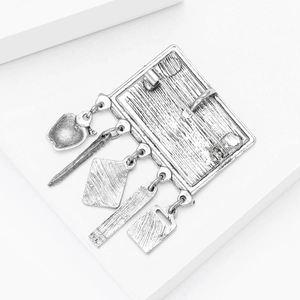 Detailed close-up of retro silver blackboard brooch with school themed stationery charms
