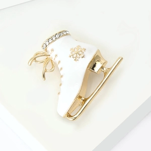 Detail of ice skate brooch with white enamel, crystal rhinestones and golden snowflake pattern