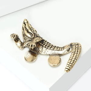 Detailed relief texture of vintage gold crocodile brooch showing scaly metal finish