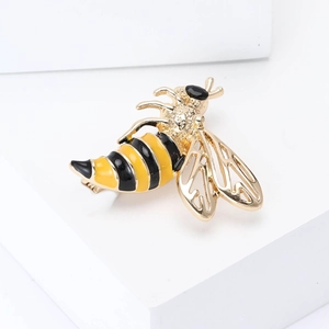 Macro detail of bee brooch with gold finish, hollow wings and yellow enamel