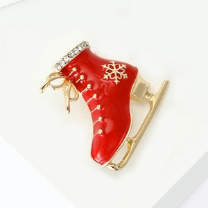 Detailed view of a red enamel ice skate brooch with gold snowflakes and sparkling crystals