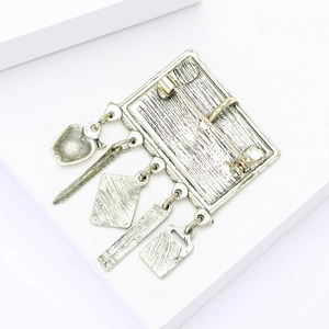 Detail of vintage silver blackboard brooch back with pin clasp and five unique metal charms