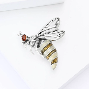 Macro detail of bee brooch featuring silver镂空 wings, enamel body and red crystal eye