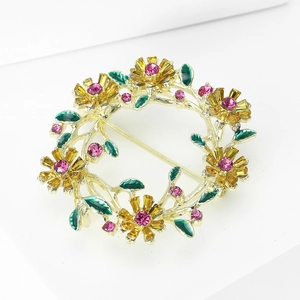 Detailansicht einer goldfarbenen Blumenkranz-Brosche mit pinkfarbenen Strasssteinen