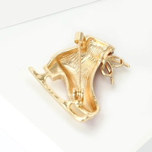 Detailed back view of gold ice skate brooch showing sturdy alloy metal and safety pin clasp