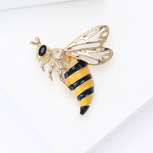 Close-up detail of a golden bee brooch with black enamel body and hollow metal wings
