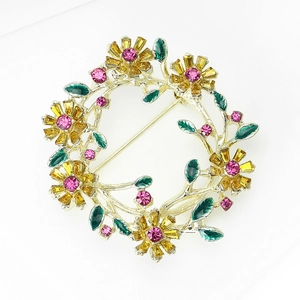 Detailansicht einer Blumenkranz-Brosche mit gelben Steinen und rosa Straßsteinen
