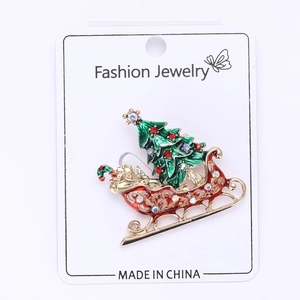 Close-up of enamel Christmas tree and red sled brooch with colorful rhinestones