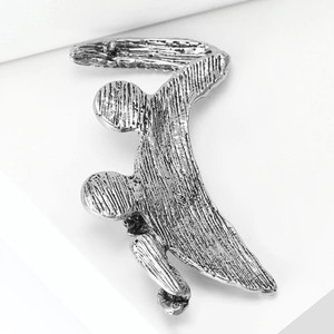 Macro shot of a silver skateboarder brooch with vintage brushed metal texture on white stand