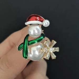 Détail de la broche bonhomme de neige avec perles blanches et chapeau émaillé rouge
