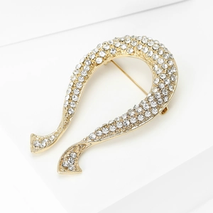 Vue détaillée d'une broche dorée en U sertie de strass sur un piédestal blanc