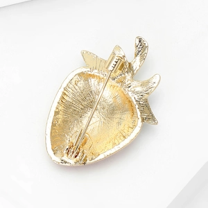Back view of a gold strawberry brooch showing the secure pin fastener and textured metal