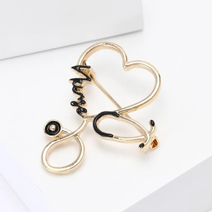Detail of gold stethoscope heart brooch with Nurse text on white geometric stand