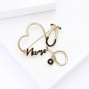 Close-up of golden heart stethoscope brooch with Nurse text on white display