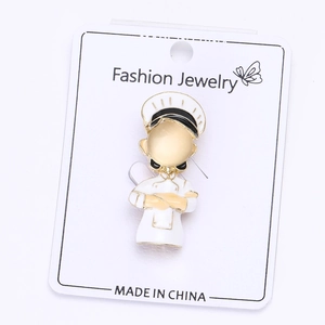 Detail of chef character enamel pin with gold plating on a white jewelry display card