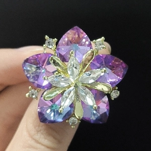 Macro shot of purple sunflower crystal brooch with golden alloy setting held by hand