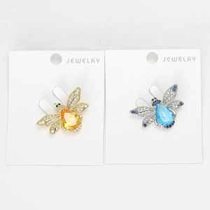 Détail de broches abeilles en or avec cristal jaune et argent avec cristal bleu ciel