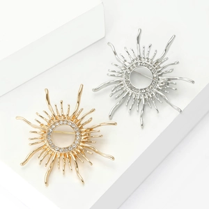 Elegant gold and silver sun hollow brooches with crystals on white geometric stand