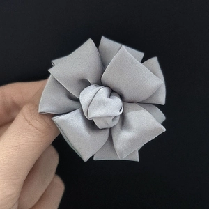 Detailed close-up of handmade grey fabric flower brooch with layered folding petals