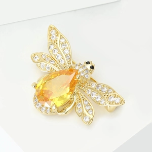 Détail macro d'une broche abeille dorée avec une pierre poire jaune et des strass fins