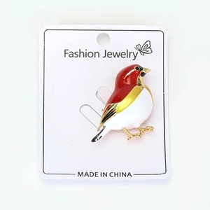 Detail of colorful enamel bird brooch pin with gold plating on a fashion display card