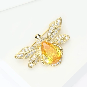 Vue macro d'une broche abeille dorée avec pierre jaune et ailes serties de cristaux