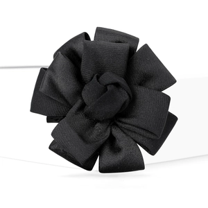 Macro shot of black satin floral brooch showing pleated texture and glossy ribbon details
