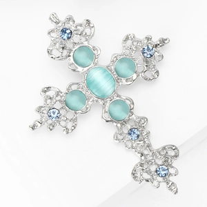 Détail d'une broche en forme de croix en alliage avec strass bleu clair et pierre d'œil de chat