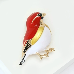 Charming enamel bird brooch in red and gold finish on a white display stand