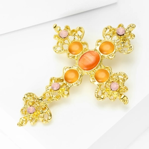 Détail d'une broche croix baroque avec opales orange et strass roses étincelants