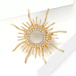 Detail of gold sunburst brooch featuring hollow center and sparkling crystal rhinestones