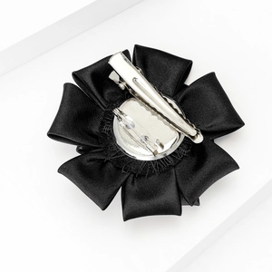 Detail view of black satin fabric flower with dual brooch pin and hair clip backing
