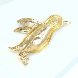 Vue détaillée du dos d'une broche pingouin dorée montrant le fermoir et la texture métal