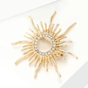 Detail of a golden sunburst brooch with hollow center and sparkling white rhinestones