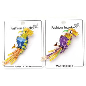 Detailed close-up of blue and purple enamel parrot brooches on a display card