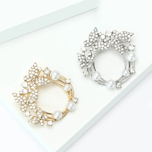 Broches florales élégantes en or et argent avec strass et perles sur socles blancs