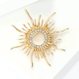 Macro detail of sunburst brooch featuring golden hollow design and sparkling rhinestones