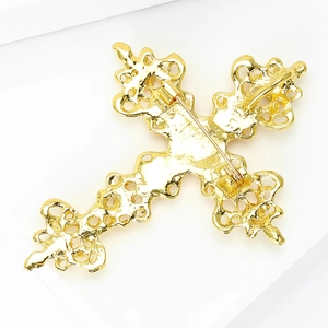 Détail de l'arrière d'une broche croix dorée avec fermoir à épingle et motifs filigranes