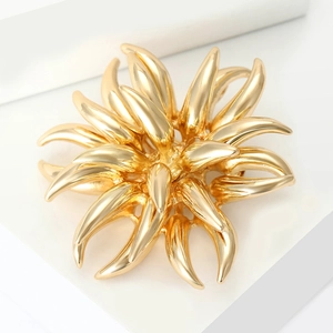 Macro shot of 3D layered golden firework brooch with polished metal finish on white stand