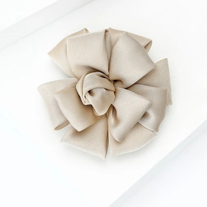 Detail of champagne gold grosgrain ribbon flower brooch with elegant layered petals