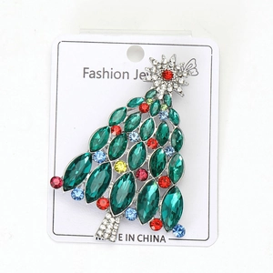 Détail d'une broche sapin de Noël avec strass colorés sur une carte de présentation bijoux