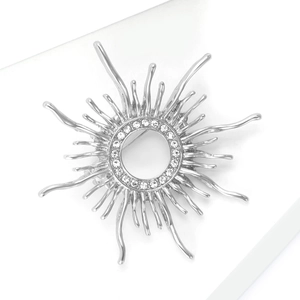 Macro detail of silver sunburst brooch with clear rhinestone center and alloy rays