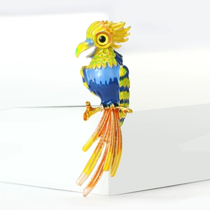 Colorful parrot enamel brooch pin in vibrant blue and yellow on a gold branch