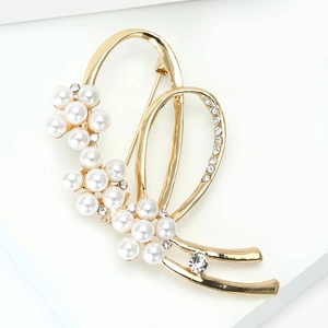 Détail d'une élégante broche en alliage doré avec perles blanches et strass étincelants